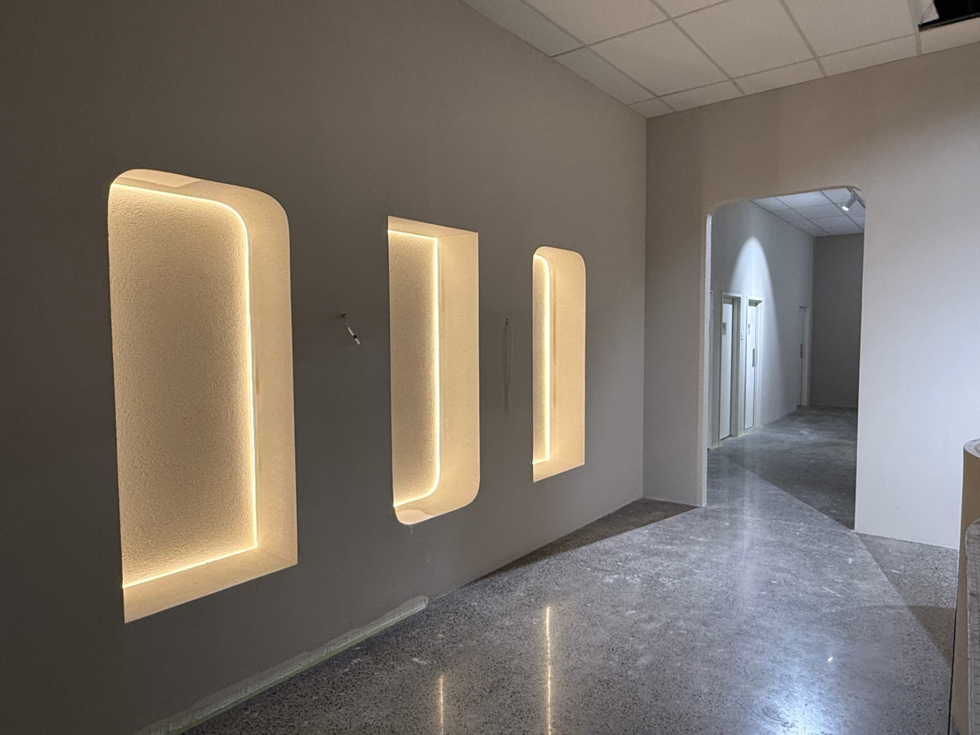 Finished feature wall with backlit arched plaster niches in a commercial interior