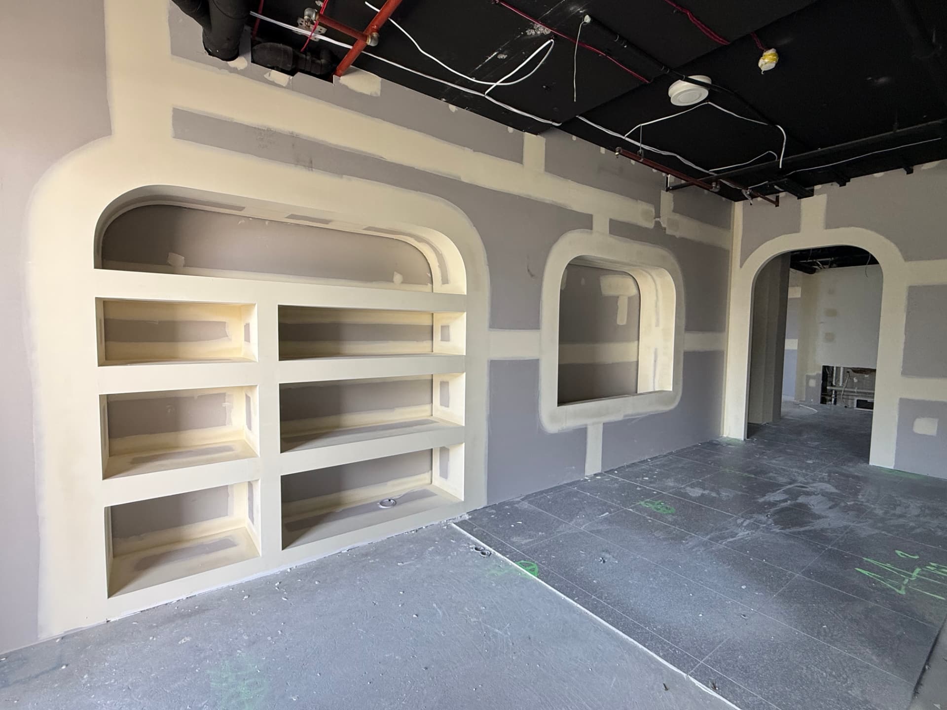 Plasterboard feature wall with arched shelving niches and curved archway in a retail fit-out