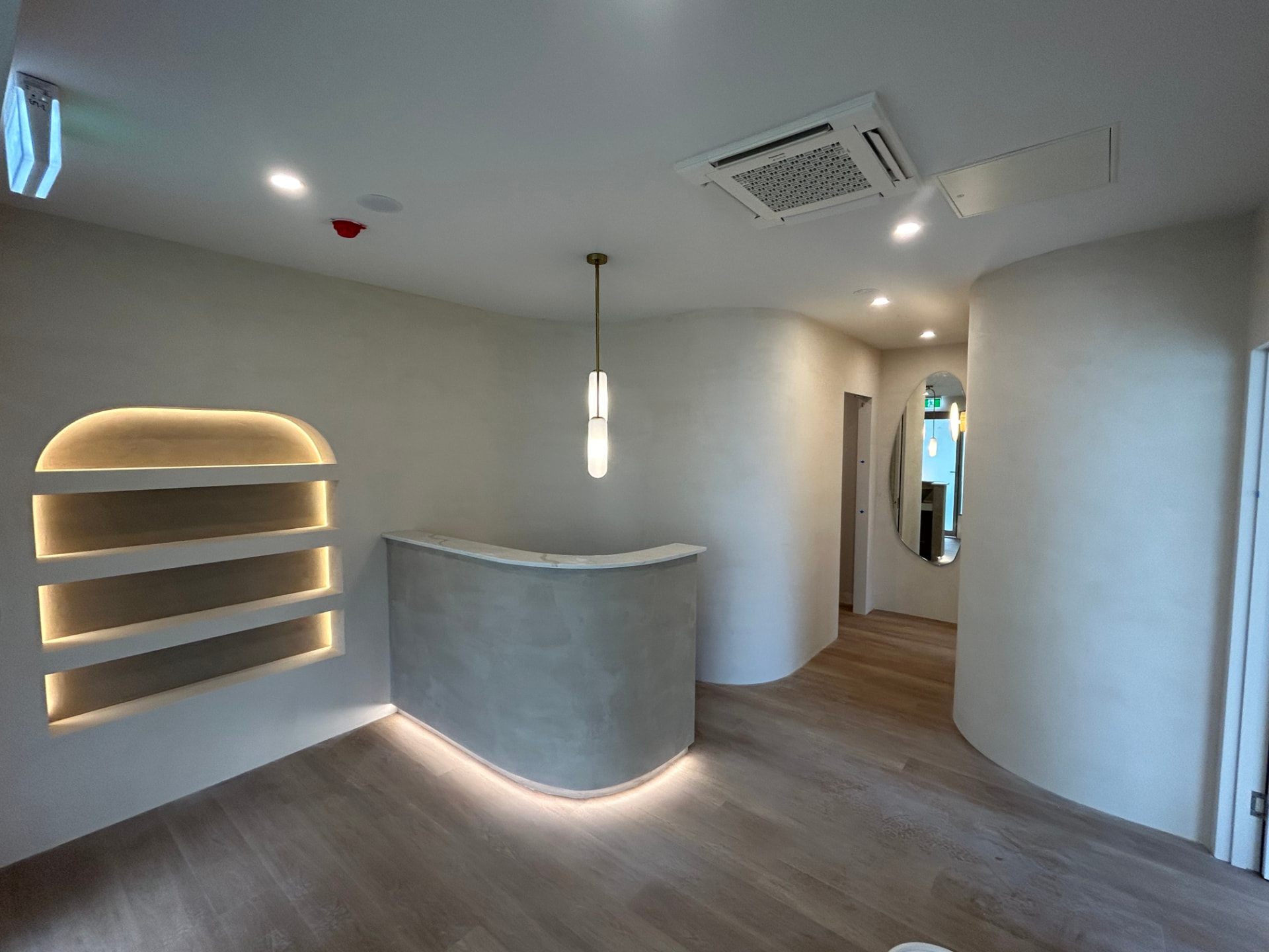 Completed commercial fit-out with curved plaster walls, arched shelving niche and rendered reception counter